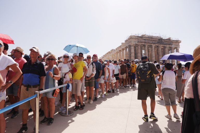 Visitors walk near the Parthenon atop the Acropolis in Athens