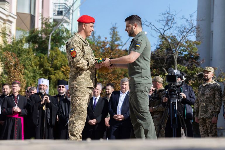 Ukrainian President Volodymyr Zelenskyy, centre right, awards a serviceman during an event for marking Statehood Day in Kyiv, Friday, July 28, 2023 [Ukrainian Presidential Press Office via AP]