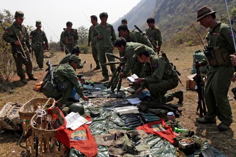 Soldiers with the MNDAA looking at weapons they've captured from the Myanmar military/