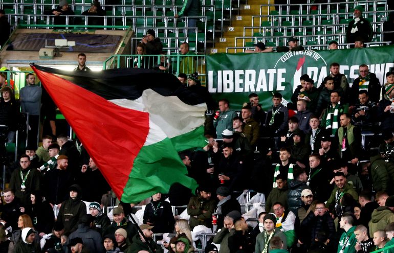 Celtic fans wave a Palestinian flag and display a banner saying ‘Liberate Palestine’ ahead of the match against Atletico Madrid