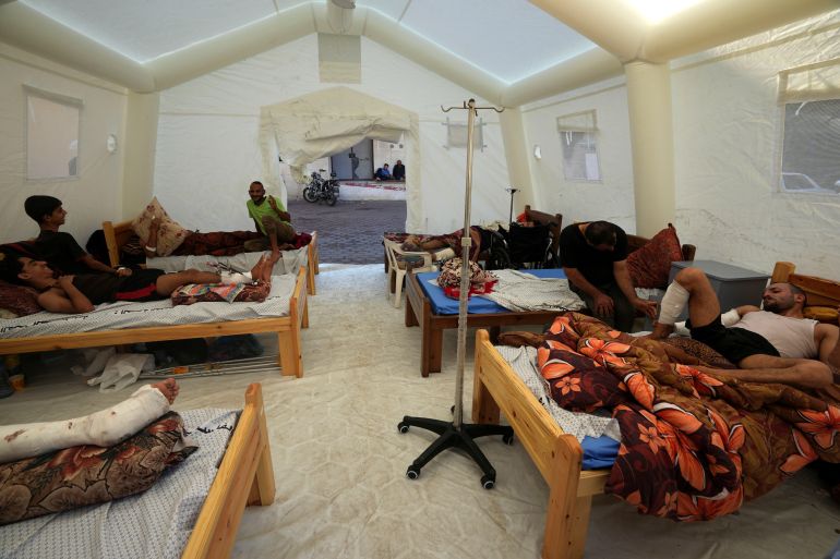 Injured Palestinians rest in a tent set up outside a hospital in the Deir el-Balah area of the central Gaza Strip on October 16