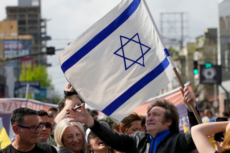 Then-candidate Javier Milei lifts up an Israeli flag during a campaign rally in Lomas de Zamora, Argentina, on October 16