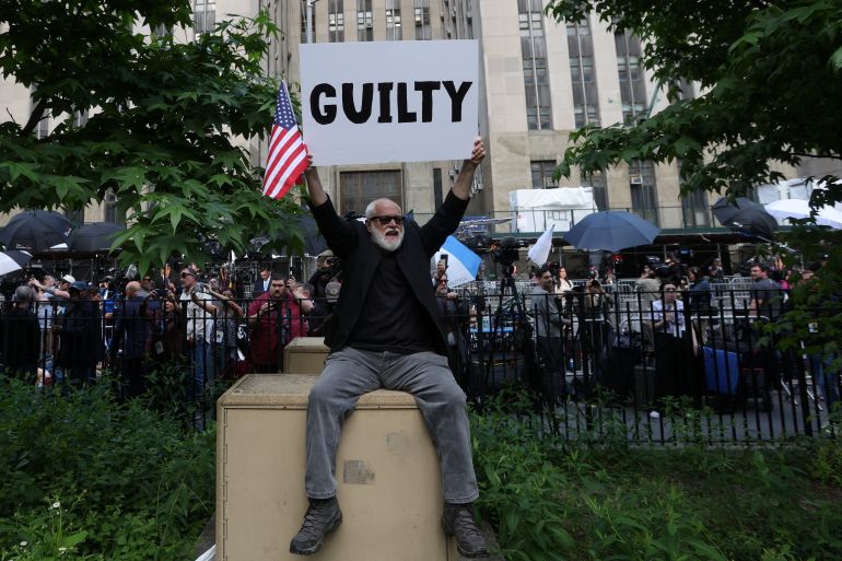 A protester outside the Manhattan Criminal Court holds up a sign that announces the guilty verdict on May 30