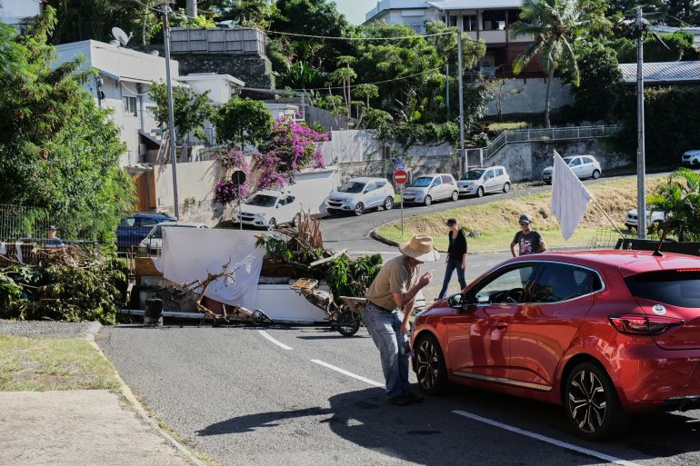 A resident speaks to a motorist at a temporary barricade, set up by residents with the aim of keeping watch over their neighbourhood in a peaceful manner, in the Magenta district of Noumea on May 16, 2024