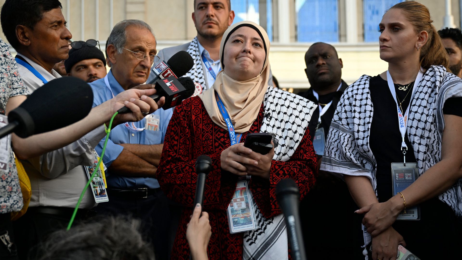 Ruwa Romman, with a keffiyeh draped over one shoulder, speaks at a press conference outside the Democratic National Convention.