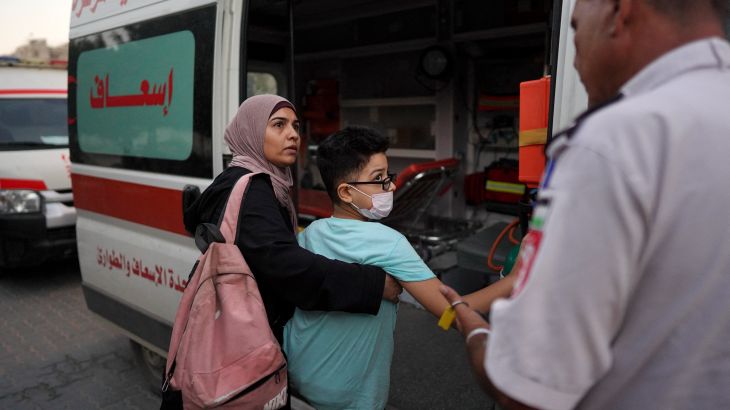 A woman helps a relative get in an ambulance at Al-Nasser hospital in Khan Yunis on August 15, 2024, after permission from the Israeli authorities was given for 11 children suffering from cancer to leave Gaza through the Kerem Shalom crossing