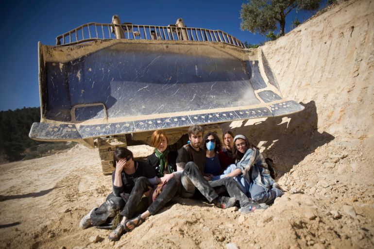 Israeli and international activists sit in front of a bulldozer during a protest against the construction of Israel’s separation barrier in the occupied West Bank village of al-Walaja in 2011