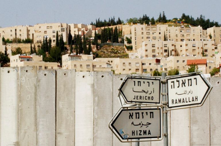 The Jewish settlement of Pisgat Ze’ev is visible behind a section of Israel’s separation barrier, as road signs point to the Palestinian towns of Jericho, Ramallah, and Hizma, in the occupied West Bank village of Hizma, near Jerusalem, in 2005. Israel took inspiration from apartheid South Africa’s racial segregation policies