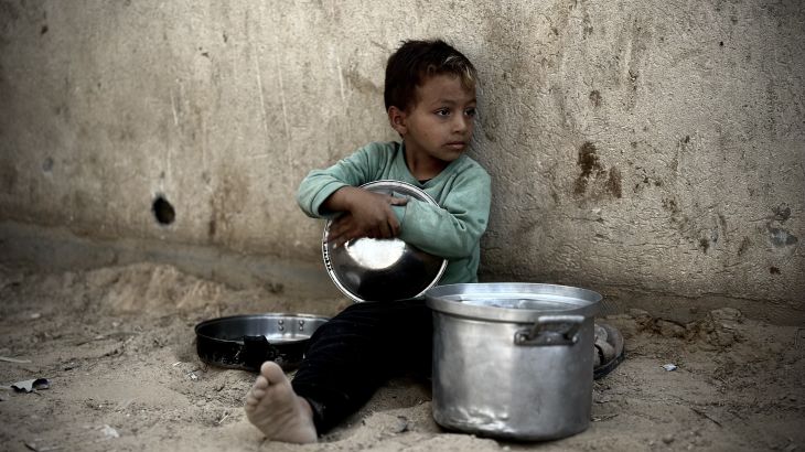 Palestinian child is seen with a pot as he waits to receive the food distributed by charitable organizations