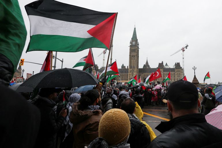Protesters hold Palestinian flags during a rally in front of the Canadian parliament in Ottawa