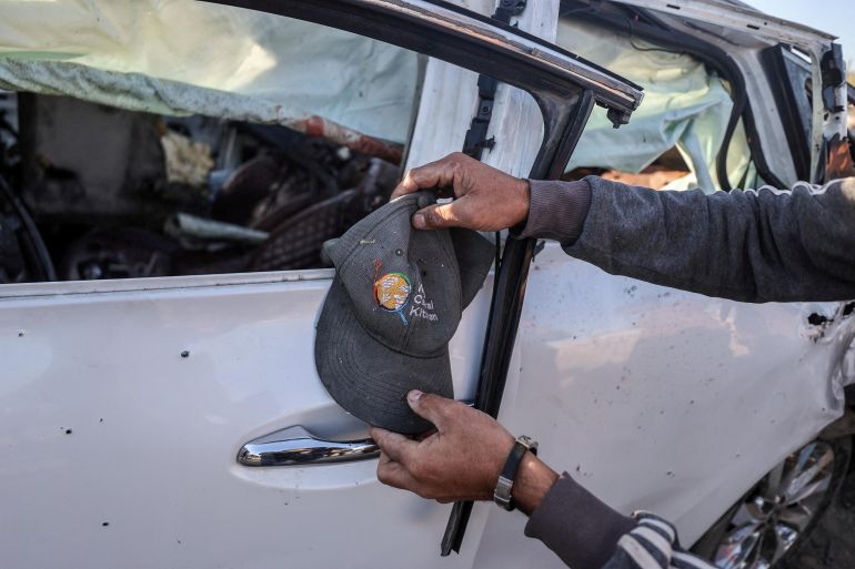 A man holds a cap next to a vehicle in which WCK employees were killed