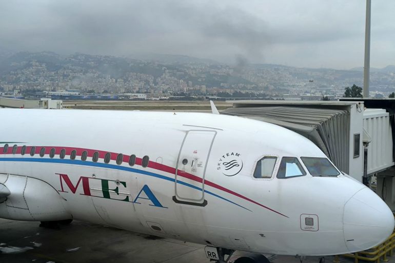 Smoke billows in the background from the site of an Israeli airstrike that targeted a neighbourhood in Beiruts southern suburbs as a Middle-East Airlines (MEA) Airbus A320 aircraft awaits passengers in Beiruts international airport tarmac, on October 10, 2024. - As Israel ramped up air strikes against Lebanese armed group Hezbollah two weeks ago, most airlines stopped flying to the country. National carrier Middle East Airlines (MEA) remains the only carrier still serving Beirut despite the mounting risks and past hits on the runways. (Photo by Janine HAIDAR / AFP)