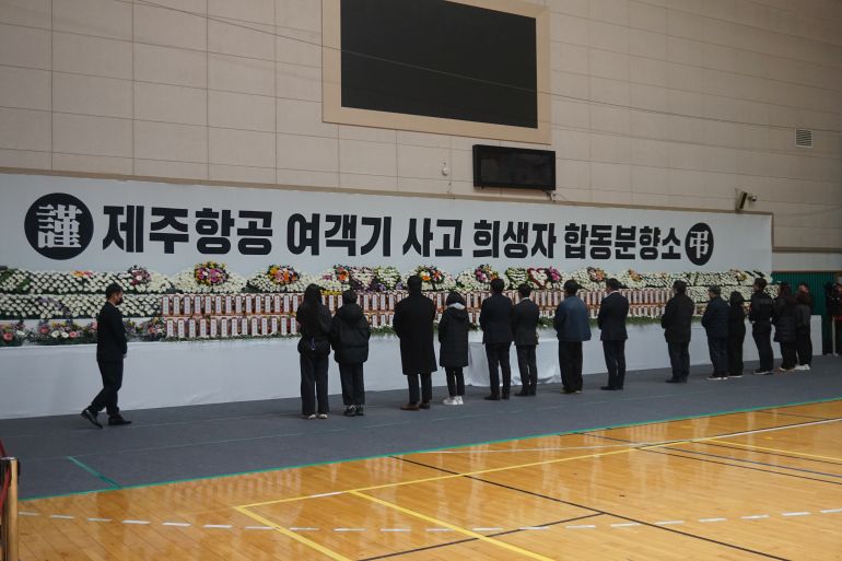 People pay respect to victims of the plane crash at a memorial altar inside Muan Sports Park