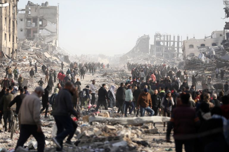 Displaced Palestinians walk past the rubble as they attempt to return to their homes.