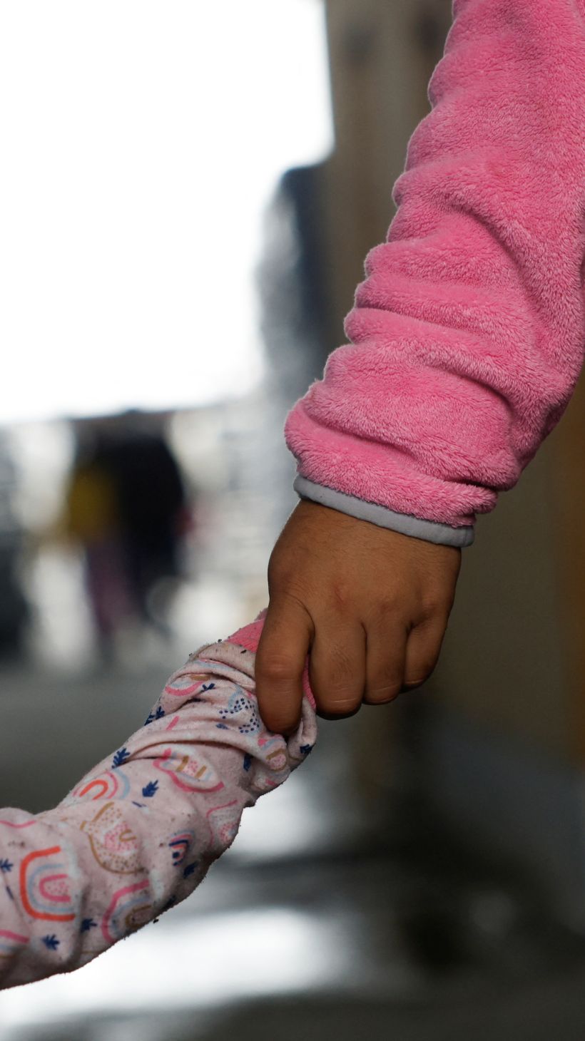 A young child holds hands with their parent in Reynosa, Mexico