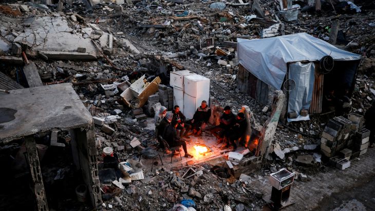 Palestinians gather near a fire next to the rubble of destroyed buildings, amid a ceasefire between Israel and Hamas, at Jabalia refugee camp, northern Gaza Strip