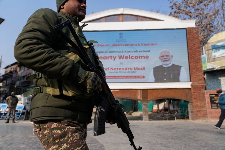 An Indian paramilitary soldier patrols near an electronic display in Srinagar, welcoming Modi to inaugurate the Z-Morh strategic tunnel on January 13, 2025