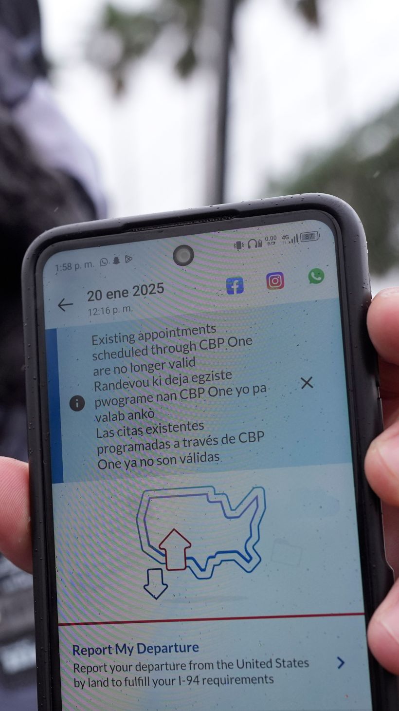 A migrant holds up a phone screen that shows CBP One is no longer available.