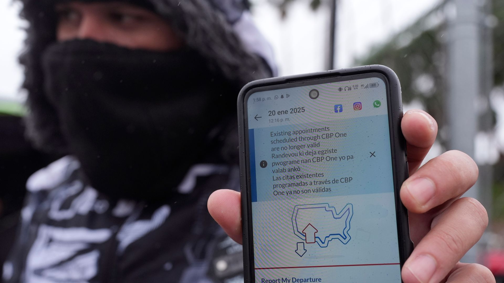A migrant holds up a phone screen that shows CBP One is no longer available.