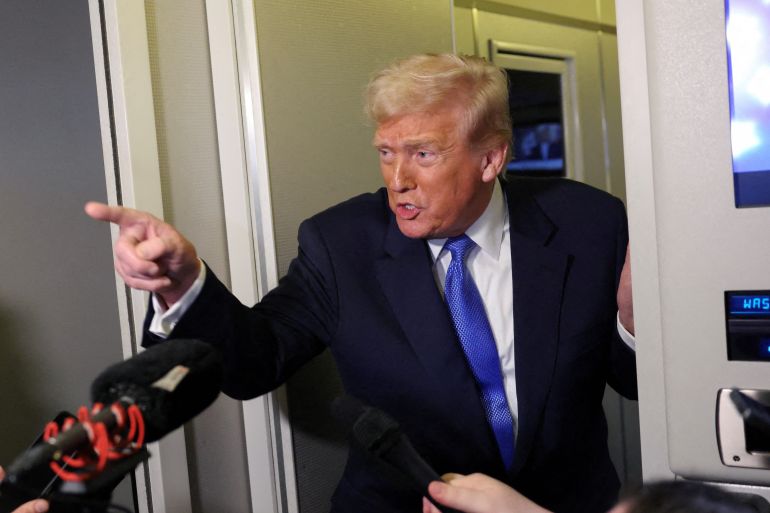 US President Donald Trump speaks to reporters as White House Press Secretary Karoline Leavitt stands with him.