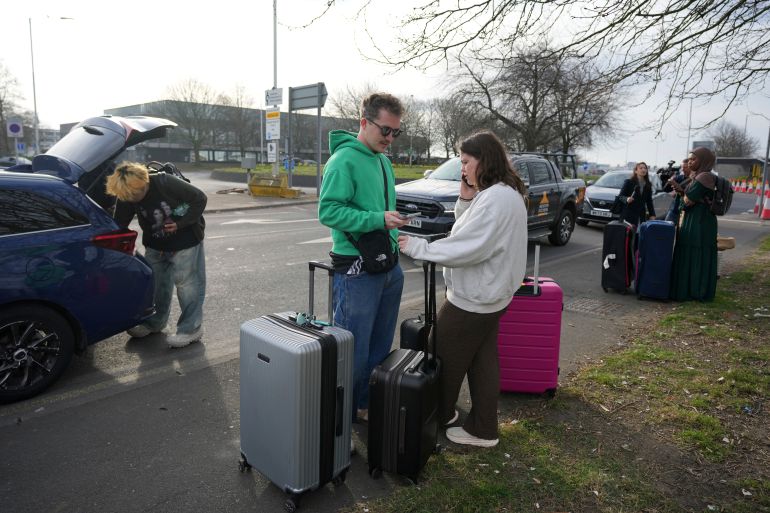 Passengers with suitcases wait on a nearby road after an electrical substation fire knocked out power to London’s Heathrow airport on Friday, disrupting flights for hundreds of thousands of passengers at one of Europe’s biggest travel hubs