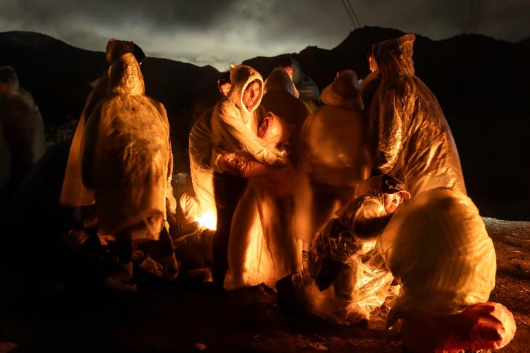 Chinese migrants warm themselves under a cold rain after crossing the US-Mexico border, Campo, California, on March 7, 2024