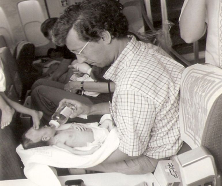 Burkle feeds an infant adoptee on board the plane he accompanied out of Saigon [Courtesy of Frederick Burkle]