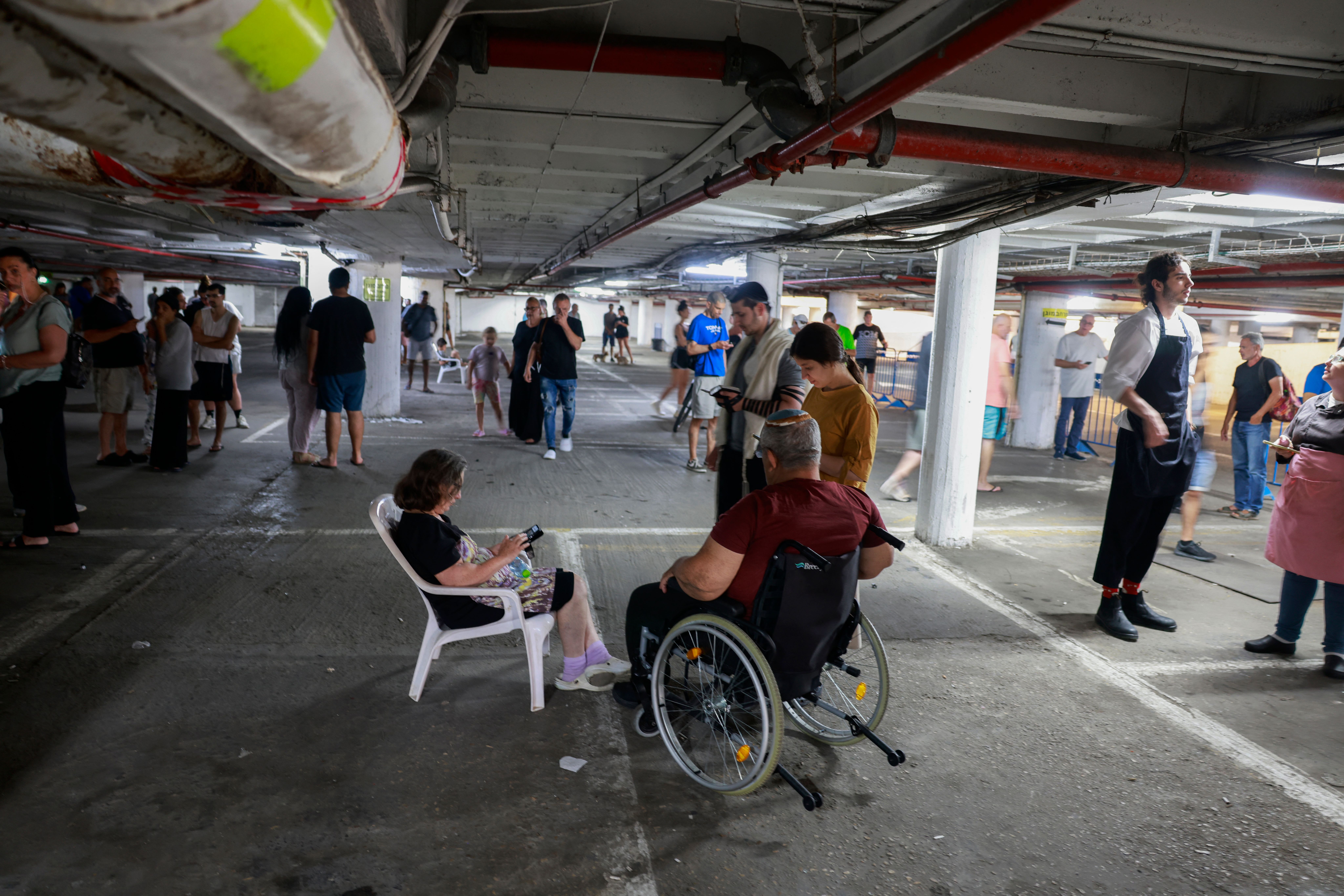 People take shelter in a parking lot in Tel Aviv amid a fresh barrage of Iranian rockets on June 17, 2025.