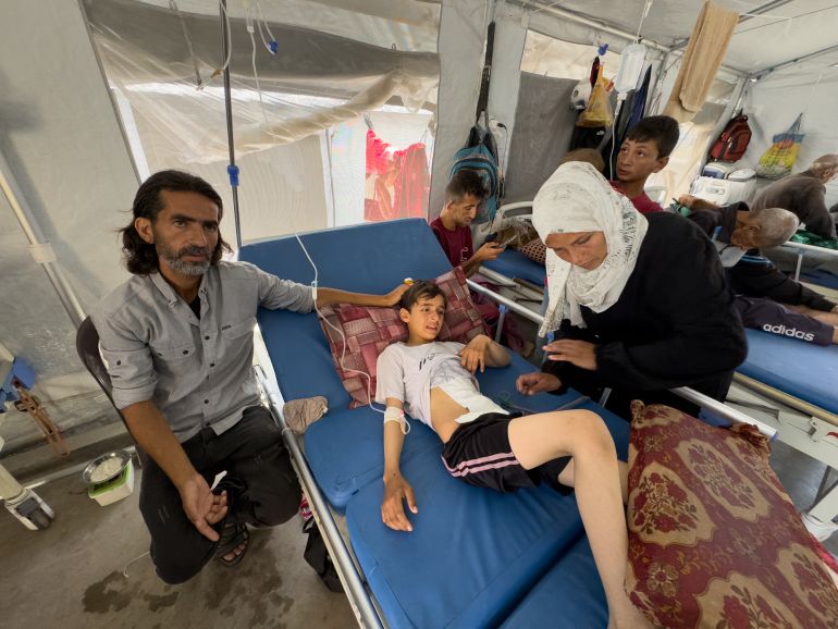 Ihab, left, and Iman Musleh hover near their son, Yazan’s, hospital bed in the makeshift tent ward