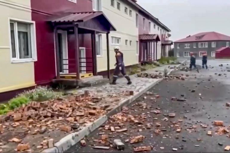 A still image taken from a handout video provided by the Russian Emergencies Ministry shows rescuers walking among debris in front of a damaged building following an earthquake, in Petropavlovsk-Kamchatsky, Kamchatka