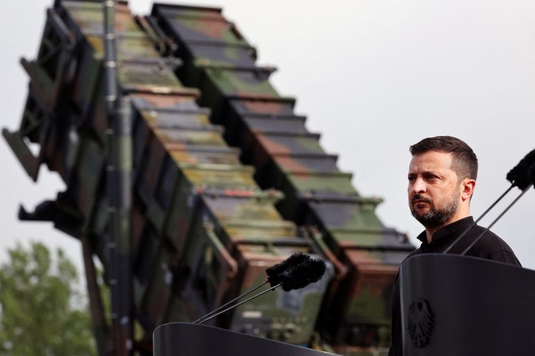 Ukrainian President Volodymyr Zelenskiy looks on during a visit to a military training area.
