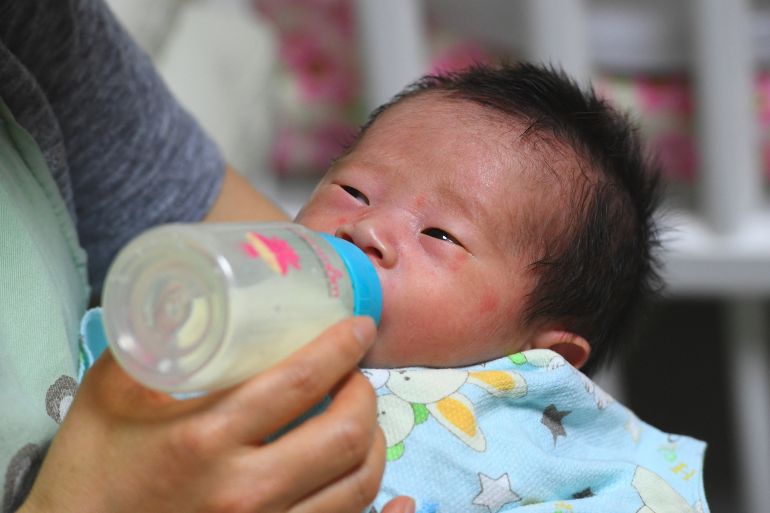 Social workers bottle-feeding a baby.