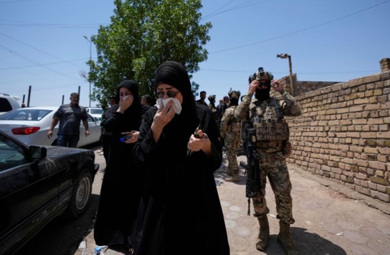 Iraqis gather in front of a burning hypermarket building in Kut, Iraq, Thursday, July 17, 2025