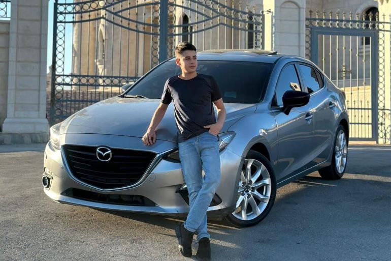 teenager in a black shirt leaning on a silver car