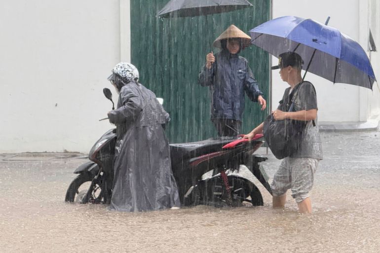 People push a motorbike through floods from heavy rains.