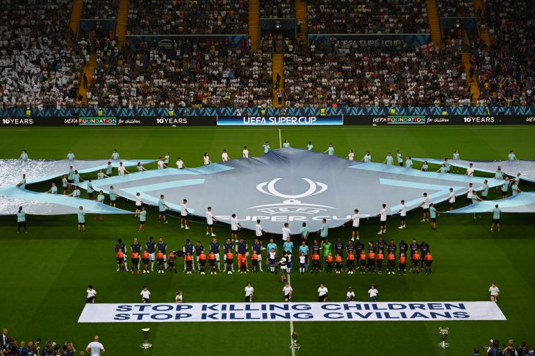 A banner which reads 'Stop killing children - Stop killing civilians' is displayed as players of both side's line up prior to during the UEFA Super Cup 2025 match between Paris Saint-Germain and Tottenham Hotspur