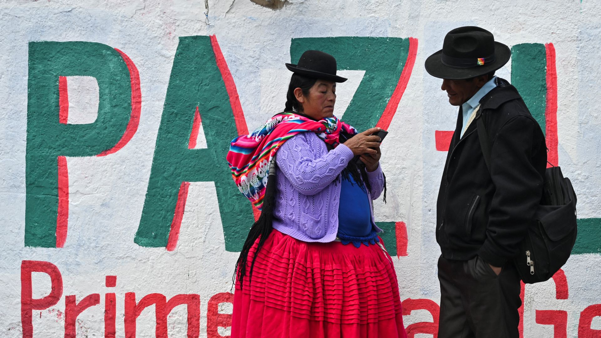 Supporters stand in front of a mural with Paz's name.
