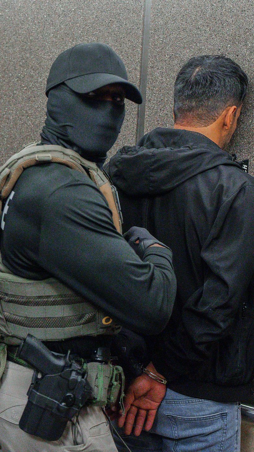 Immigration and Customs Enforcement agents escort a detaining migrants. [File: Olga Fedorova/AP