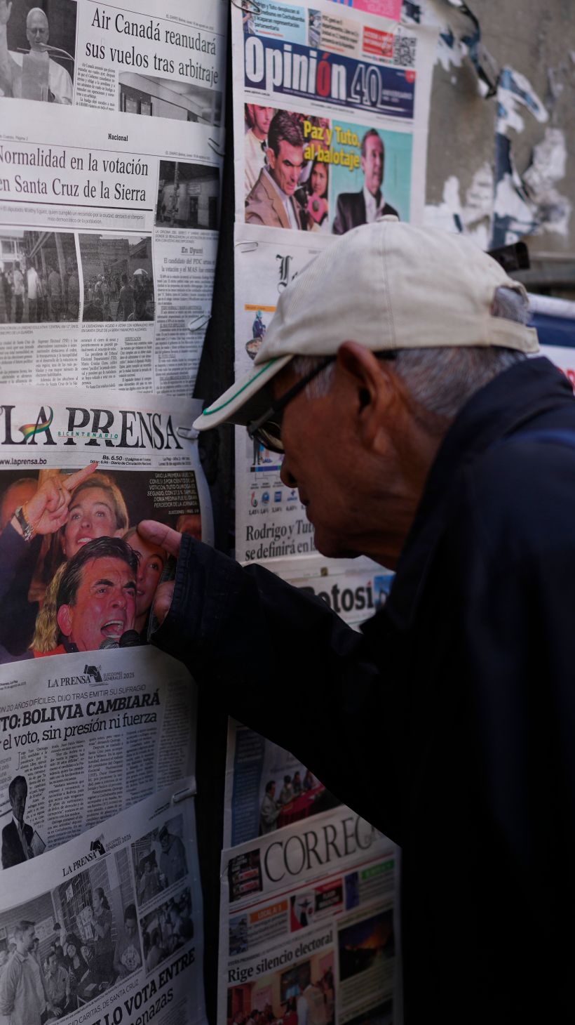 A man looks at newspapers with election results pinned to the wall