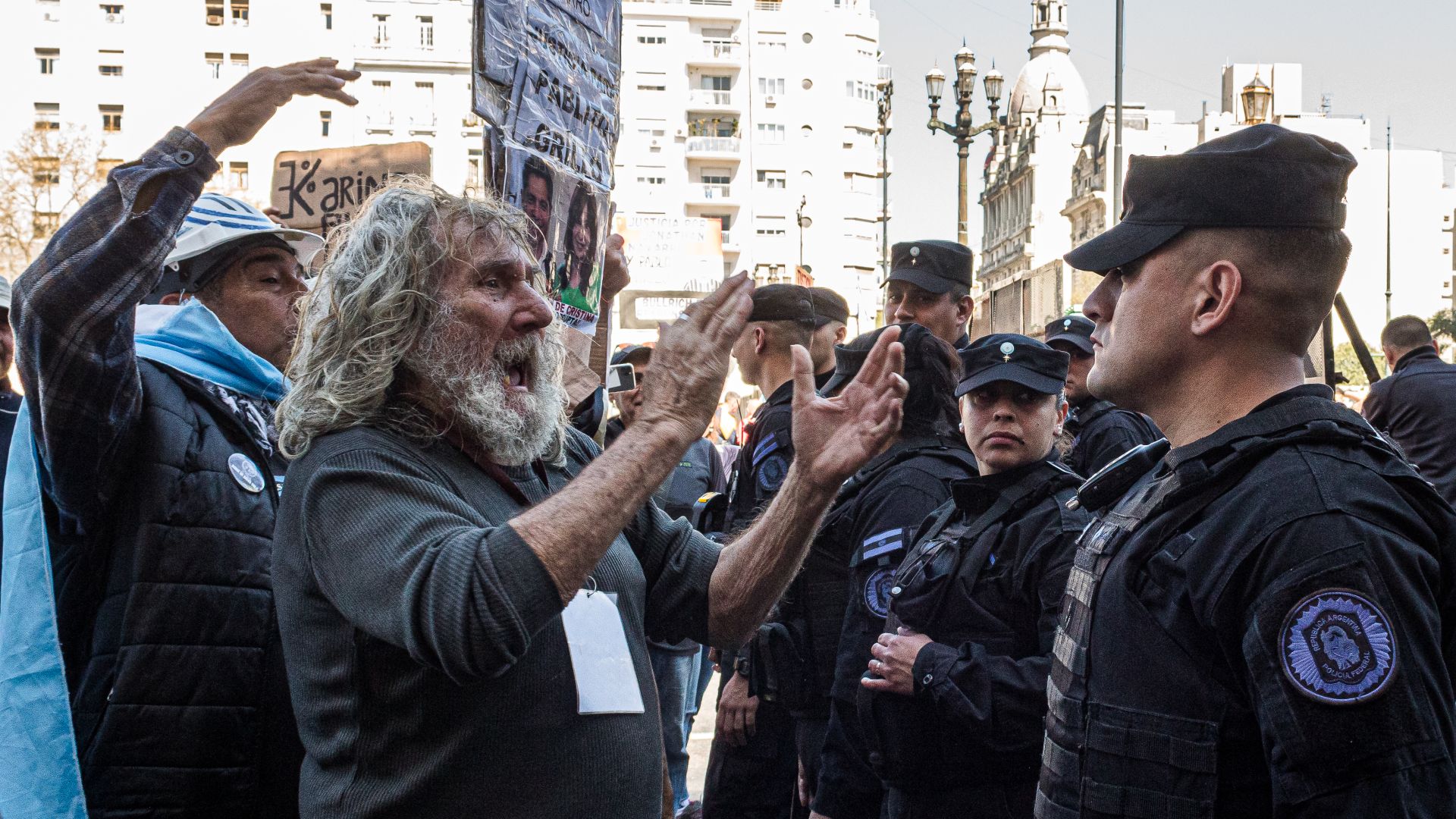 Elderly protesters yell in front of a line of police officers