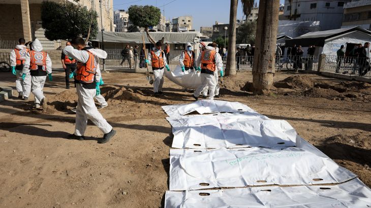 Members of the Palestinian Civil Defence work to exhume bodies of people killed in Israeli raids for reburial at al-Ahli Arab Hospital in Gaza City
