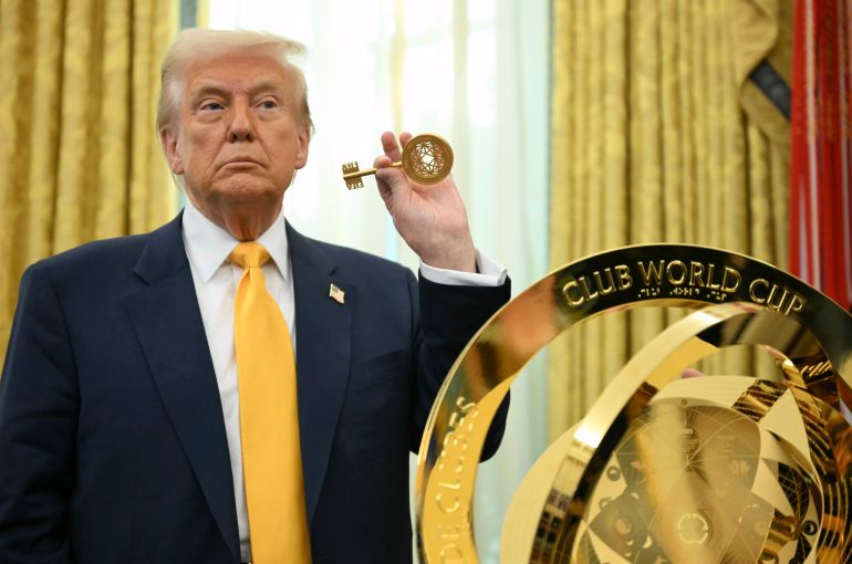 Trump holds up a key in front of the FIFA Club Cup Trophy