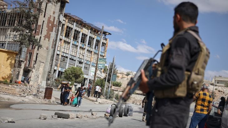 Syrian security forces stand guard as residents leave a neighbourhood.
