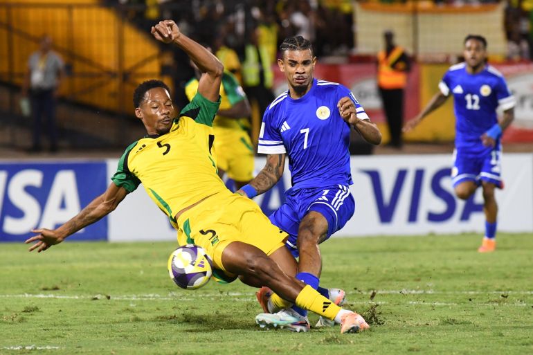 Curaçao's Juninho Bacuna, center, fight for the ball against Jamaica's Ethan Pinnock, left, during a World Cup 2026 qualifying soccer match in Kingston, Jamaica, Tuesday, Nov. 18, 2025. (AP Photo/Collin Reid)