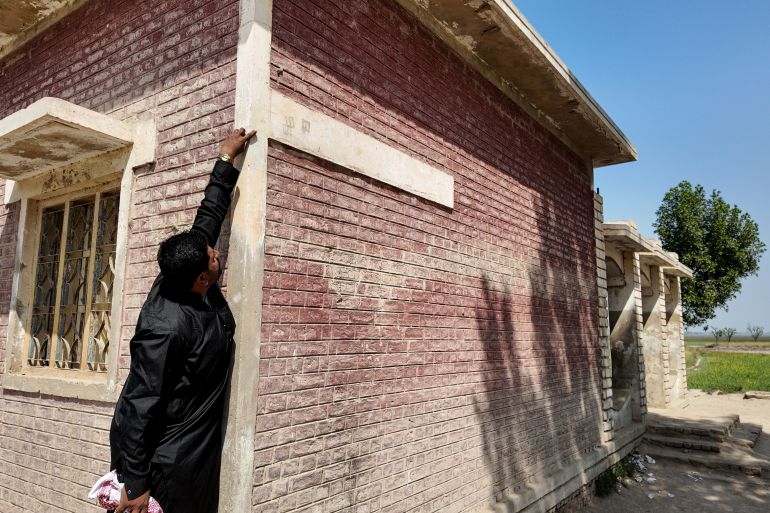 Laghari showing the faint mark left by floodwaters at a school in Dadu [Al Jazeera]