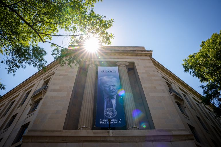 WASHINGTON, DC - MAY 18: A large image of U.S. President Donald Trump hangs from the the Robert F. Kennedy Department of Justice Building on May 18, 2026 in Washington, DC. The Justice Department has announced the creation of a nearly $1.8 billion compensation fund for allies of U.S. President Donald Trump who allege they were unfairly targeted by the federal government under the previous administration. Andrew Harnik/Getty Images/AFP (Photo by Andrew Harnik / GETTY IMAGES NORTH AMERICA / Getty Images via AFP)