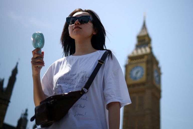 A woman uses a fan as she walks near the Houses of Parliament, amid hot weather in London, Britain, June 23, 2026. REUTERS/Guglielmo Mangiapane TPX IMAGES OF THE DAY