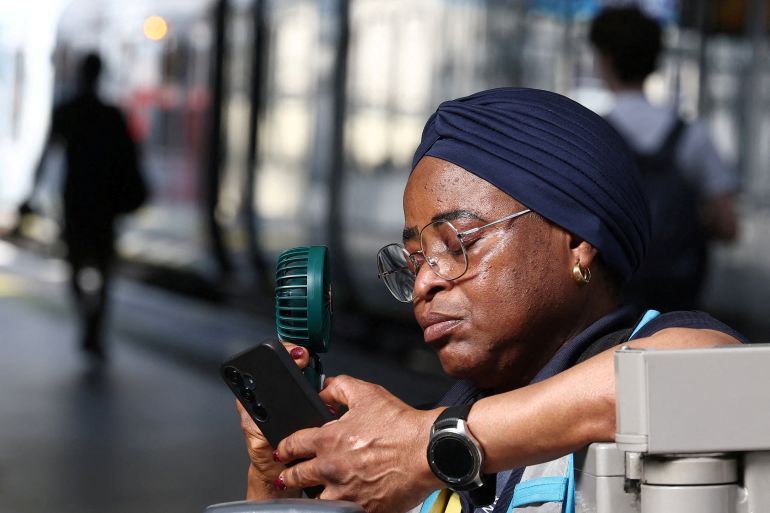 A railway revenue protection officer uses a fan to cool down on a rail platform as Britain experiences record temperatures disrupting schools and transport networks, at Waterloo Station in London, Britain, June 24, 2026. REUTERS/Toby Melville TPX IMAGES OF THE DAY