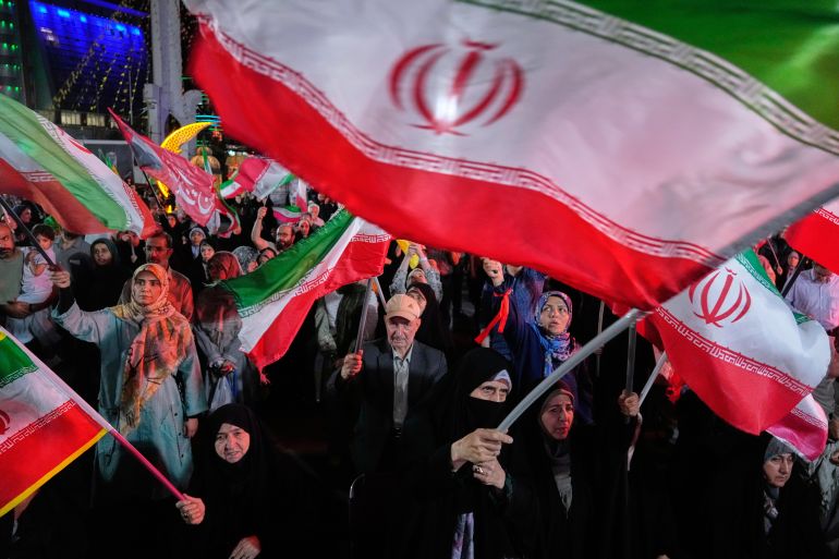 Demonstrators wave Iranian flags in a pro-government gathering in Tehran, Ira