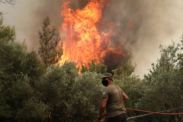 A firefighter tries to extinguish a fire in the village of Avgaria, on the island of Evia, Greece, August 10, 2021. REUTERS/Stelios Misinas